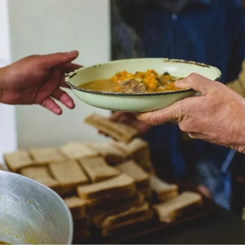 Volontari servono un piatto di pasta in una mensa solidale