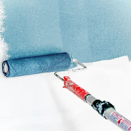 Rullo da pittura con vernice azzurra su una parete